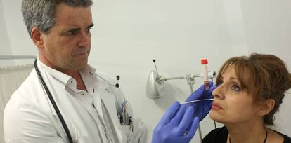 El médico Ruiz Maroto toma una muestra a una mujer para diagnosticar la gripe.