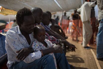 Un hombre espera junto a su hija en el hospital de campaña de Médicos Sin Fronteras en un campo para refugiados de Juba.