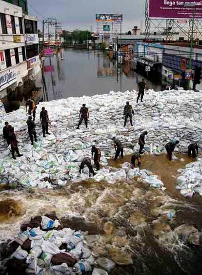 Los soldados construyen un dique con sacos para contener el agua.