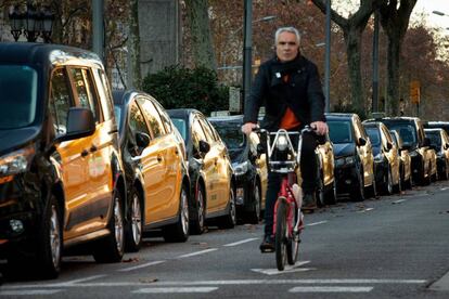 Un home circula amb bicicleta per la Gran Via de Barcelona, on hi ha estacionats per quart dia consecutiu els taxistes de Barcelona.