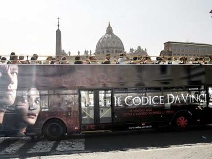 El anuncio de <i>El código Da Vinci</i> en un autobús <i>enmarca,</i> el viernes, la cúpula de San Pedro, en el Vaticano.