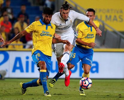 Gareth Bale (c) del Real Madrid golpea el balón con la presión de Aythami Artiles (i) de UD Las Palmas.