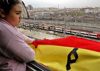 Elena, de 12 a?os, cuelga una bandera espa?ola con un crespn negro en el balcn desde el que se la estacin de Atocha. El lazo se ha convertido en el smbolo del dolor y la repulsa a los atentados. Luce en las ventanas de miles de casas y empresas de toda Espa?a, pero tambin en las televiones y en pginas web cmo la del famoso buscador Google.