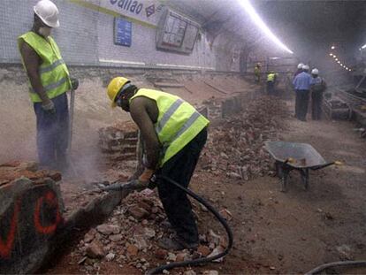 Dos obreros inmigrantes trabajan con un martillo neumático en las obras de la estación de metro de Callao.