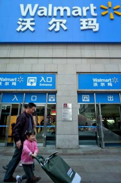 Un hombre y su hija empujan un carrito de la compra mientras caminan junto a un walmart en Qingdao (China). EFE/Archivo