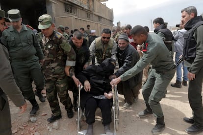 Soldados sirios ayudan a una mujer en silla de ruedas mientras abandona, junto a cientos de civiles, la zona de Guta Oriental, en la zona rural de Damasco (Siria).