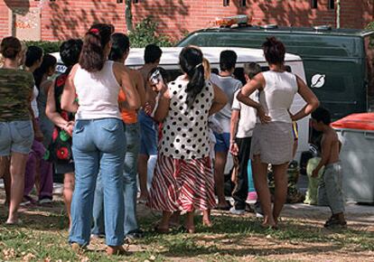 Decenas de vecinos de Moratalaz se arremolinan expectantes ante la furgoneta de la funeraria durante el traslado de los cadáveres.