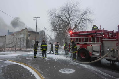 Bomberos intentan sacar el hielo de su manguera mientras trabajan por detener el incendio de un almacén, en Detroit, el 23 de diciembre.