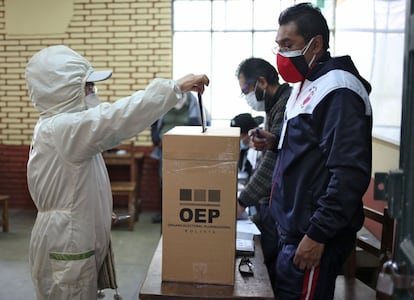 En Bolivia el voto es obligatorio y el índice de absentismo resulta tradicionalmente muy bajo (entre el 10% y el 15%). En la imagen, una mujer protegida para la covid introduce su papeleta en un centro de la capital de Bolivia.