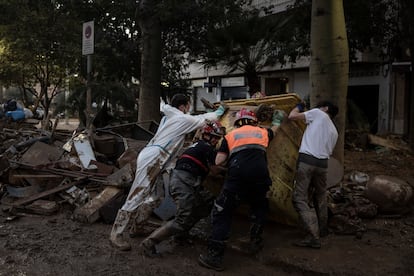 Bomberos y voluntarios trabajan en las tareas de limpieza en una calle de Paiporta, este lunes.