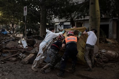 Bomberos y voluntarios trabajan en las tareas de limpieza en una calle de Paiporta, este lunes. 