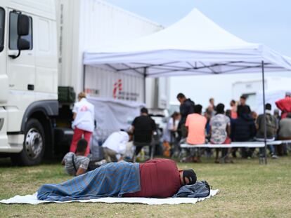 Un hombre descansa en el suelo en el exterior de un centro de asilo en Ter Apel (Países Bajos) con falta de plazas, en agosto del año pasado.