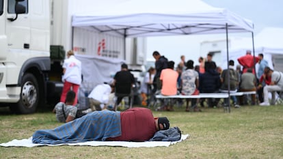 Un hombre descansa en el suelo en el exterior de un centro de asilo en Ter Apel (Países Bajos) con falta de plazas, en agosto del año pasado.