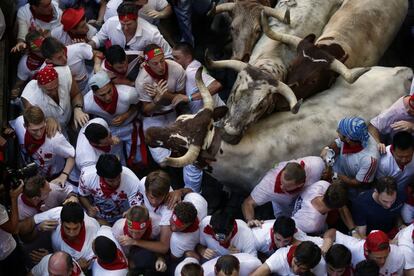 Los mozos obstaculizan el paso de los mansos en la entrada del callejón, antes de entrar en la plaza de toros, en el primer encierro.