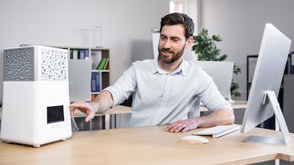 Un hombre encendiendo el calefactor de mesa en su despacho.