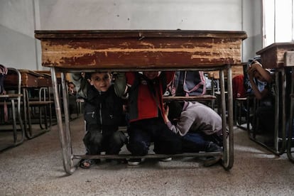 Escolares sirios aprenden a protegerse en caso de un bombardeo durante una clase de sensibilización sobre la seguridad de guerra como parte de una campaña dirigida por la defensa civil siria, conocida como The White Helmets, en la zona de Harasta, en las afueras del noreste de la capital Damas (Siria).