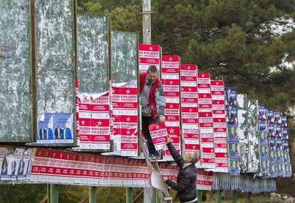 Dos hombres colocan carteles electorales en el centro de Chisinau.