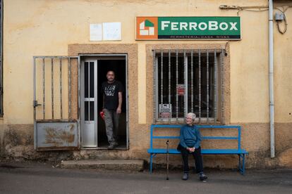 Una mujer sentada a la puerta de la tienda de alimentación y ferretería de Rabanales (Zamora), el 2 de mayo. 