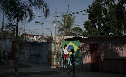 Moradora do Complexo do Alemão, no Rio de Janeiro, pinta a bandeira do Brasil numa parede.