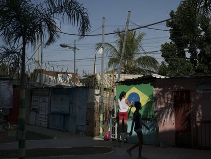 Moradora do Complexo do Alemão, no Rio de Janeiro, pinta a bandeira do Brasil numa parede.