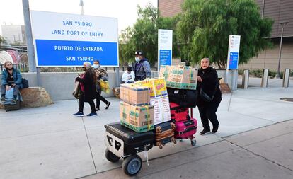 Una mujer empuja un carro con equipaje y cajas al entrar a los Estados Unidos en el puerto terrestre de San Ysidro, California.