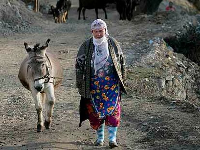 Una mujer musulmana camina con un burro en la aldea búlgara de Lazhnitsa.