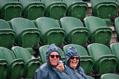 Una pareja se sienta bajo la lluvia el primer día del Campeonato de Wimbledon, el lunes 27.