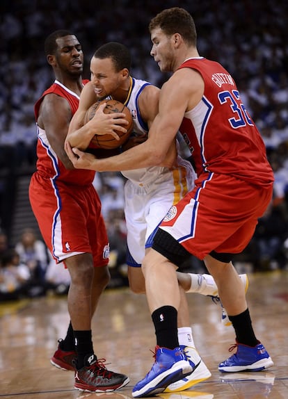 El base de los Warriors de Golden State, Stephen Curry, disputa el balón ante los jugadores de Los Ángeles Clippers Blake Griffin y Chris Paul