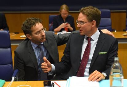 El presidente del Eurogrupo, Jeroen Dijsselbloem, agachado, habla con el finland&eacute;s Jyrki Katainen