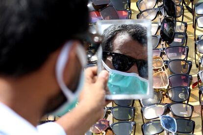 Un hombre con mascarilla se prueba unas gafas de un puesto ambulante en Karachi (Paquistán).
