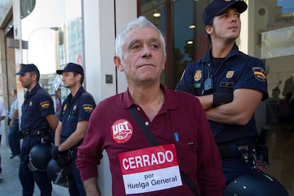 Un vecino de Málaga de avanzada edad, junto a los policías que vigilan el desarrollo de la huelga.