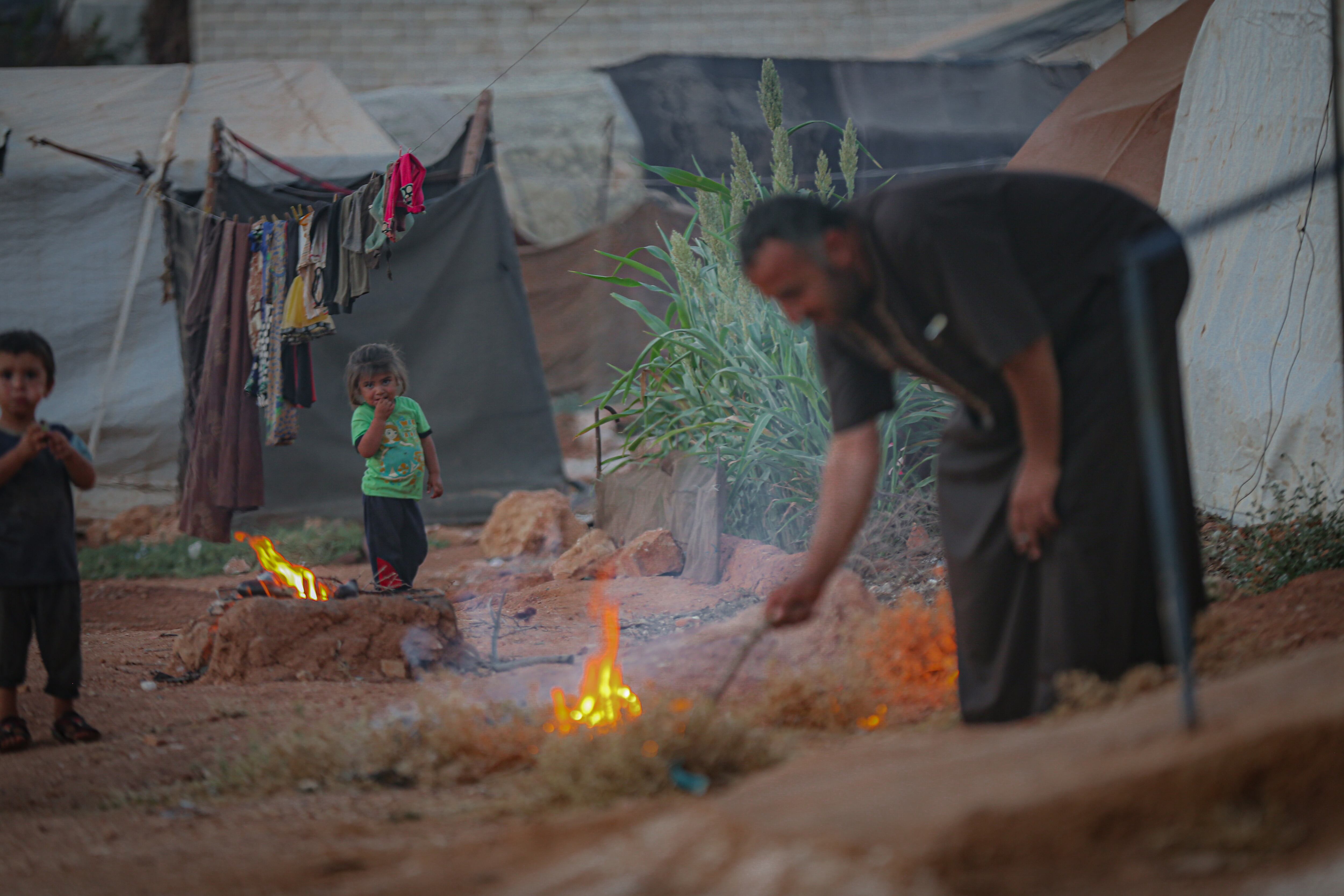 Un sirio enciende un fuego en un campo de refugiados en el área de Idlib, en 2021. 