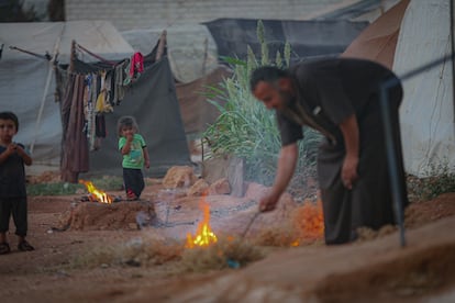 Un sirio enciende un fuego en un campo de refugiados en el área de Idlib, en 2021.