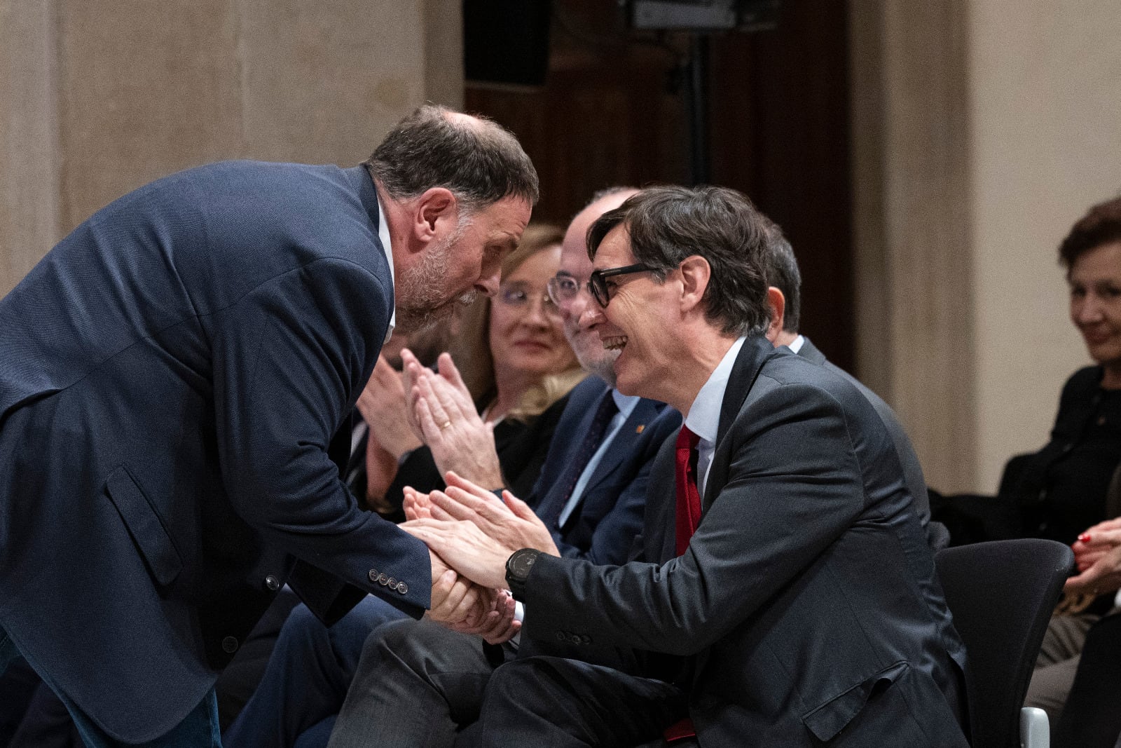 El president Salavdor Illa y el líder de ERC, Oriol Junqueras, se saludan este martes en un acto en el Palau de la Generalitat, / Carles Ribas