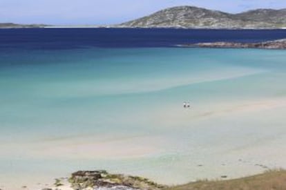 Dos turistas en una playa de la isla de Harris, en el archipiélago de las Hébridas, al norte de Escocia.