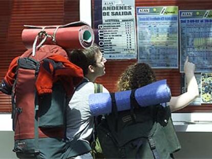 Dos viajeros miran horarios de autobús