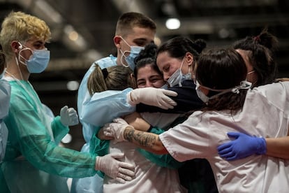Varios sanitarios se funden en un abrazo tras el último aplauso de las ocho de la tarde de este jueves para despedir lo que ha sido el hospital más grande de España para combatir la crisis sanitaria del coronavirus.