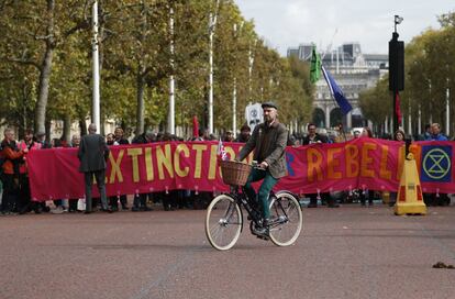 Un hombre en bicicleta cruza por delante del grupo de manifestantes climáticos mientras bloquean el centro comercial The Mall en Londres.