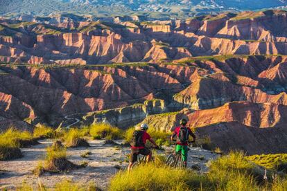 A los barrancos de arenisca roja que contemplan los ciclistas de la foto se les conoce como Los Colorados, y aunque parecen el escenario de algún 'western' ambientado en las 'badlands' de Wyoming, Dakota o Utah (EE UU), en realidad se encuentran en Gorafe, localidad granadina de la comarca de Guadix, que alberga uno de los mayores campos de dólmenes de Europa (en el pueblo también existe un centro de interpretación del megalitismo, ubicado en un recinto subterráneo con forma de dolmen). Los colores y formas erosionadas del desierto de Gorafe, un paisaje desnudo y esencial que atraviesa el río Gor, atraen a los aficionados a la fotografía de naturaleza y a las rutas en bicicleta de montaña. Al Andalus Photo Tour (alandalusphototour.com) organiza salidas de un día y talleres fotográficos de fin de semana, y la empresa The Green Bike (thegreenbike.es) ofrece rutas en bicis eléctricas o convencionales y excursiones de más de un día con alojamiento en las tradicionales casas cueva de Gorafe o Guadix.