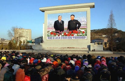 Norcoreanos se arrodillan frente a un mural con los retratos de Kim Jong Il y su padre Kim Il Sung, en una imagen distribuida por la agencia oficial norcoreana KCNA.