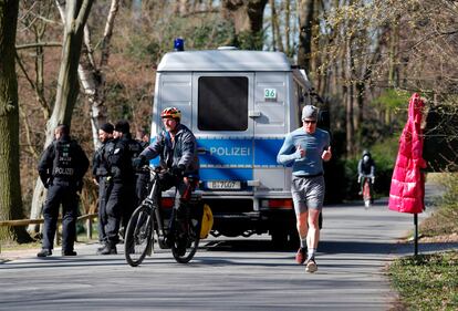 Un ciclista y un corredor pasan junto a una patrulla policial en el Tiergarten, el lunes, en Berlín.