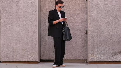 Un chico en la calle vestido con un traje y zapatillas adidas.