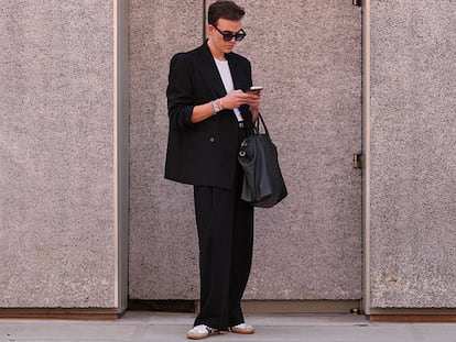 Un chico en la calle vestido con un traje y zapatillas adidas.