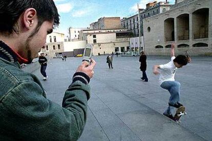 Un joven fotografía con su móvil a un niño corriendo sobre un patín en Barcelona.