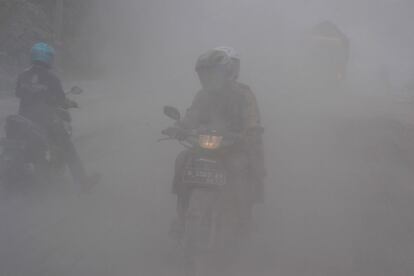 Los motoristas viajan a travs de las cenizas en una carretera en Malang, Java Oriental en 15 de febrero 2014.