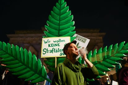 Un hombre fuma frente a un cartel que dice "No queremos ser criminales" en la Puerta de Brandeburgo, en Berlín, la noche del domingo al lunes.