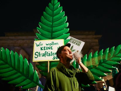 Un hombre fuma frente a un cartel que dice "No queremos ser criminales" en la Puerta de Brandeburgo, en Berlín, la noche del domingo al lunes.