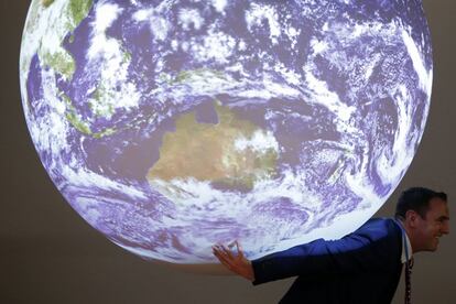 Un hombre posa con una réplica de la Tierra durante la Conferencia Mundial sobre el Cambio Climático en Le Bourget, cerca de París.