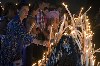 Una mujer coloca unas velas en el interior del velario del Santuario de la Virgen del Rocío.