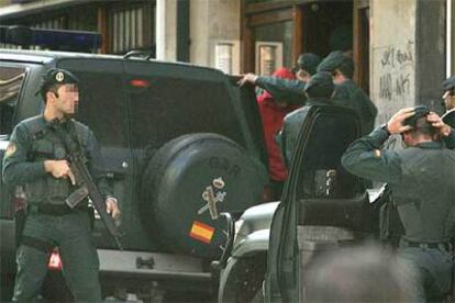 Agentes de la Guardia Civil trasladan a uno de los detenidos tras el registro efectuado en un piso de Bilbao.